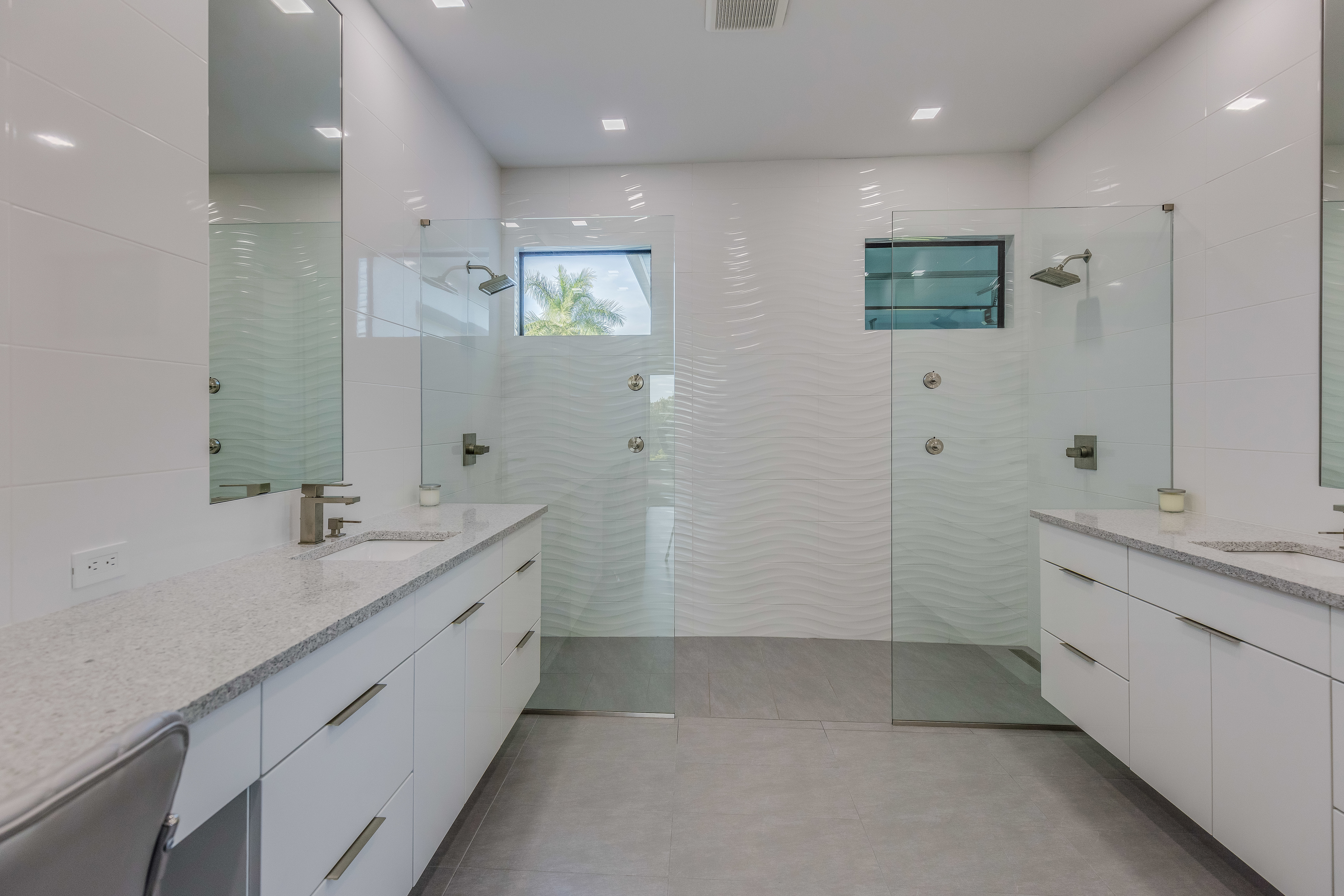 White tile bathroom with curbless, doorless walk-in shower with dual shower heads