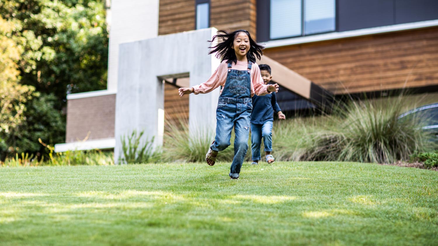 Brother and sister running in front yard