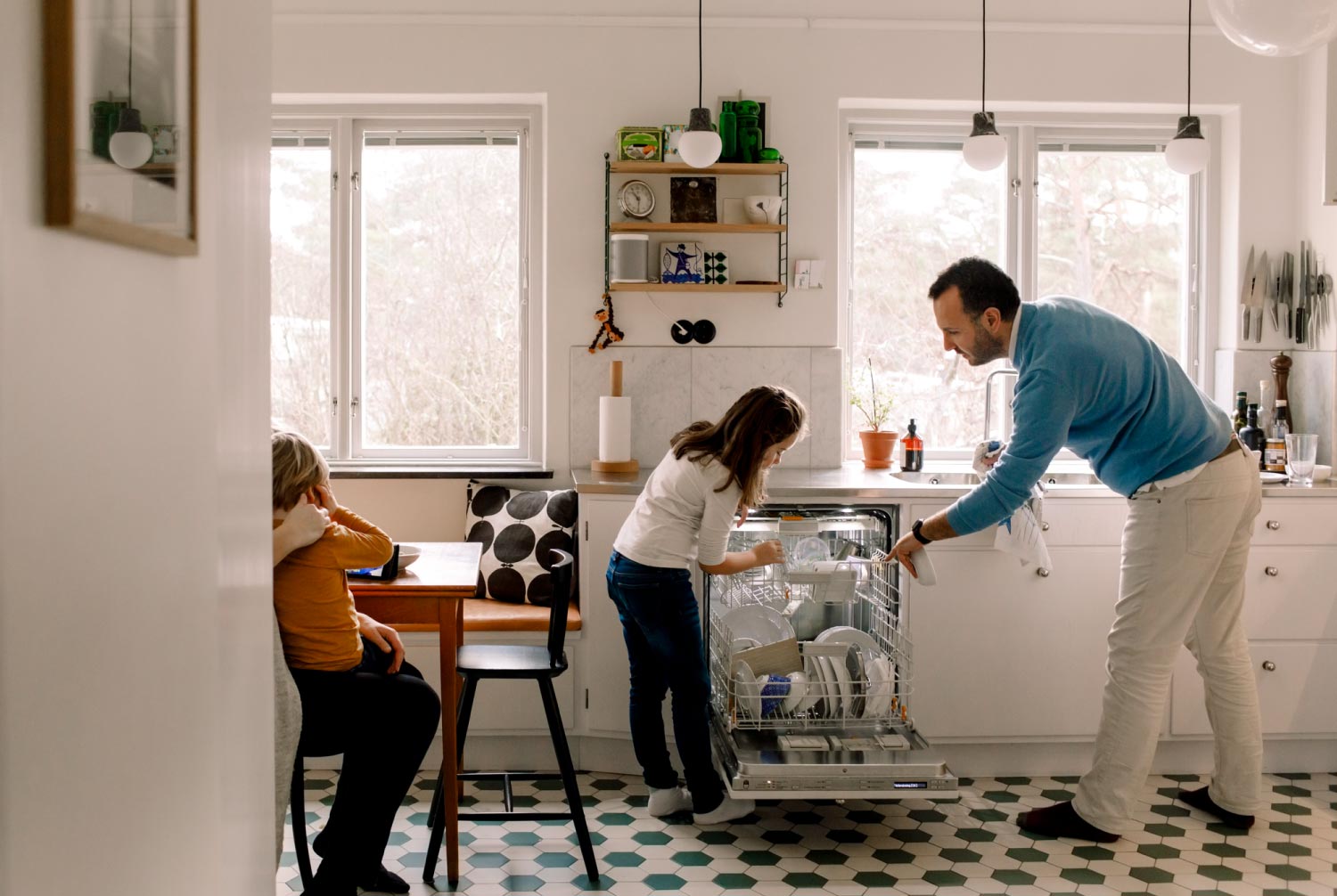 Father and daughter arranging utensils in dishwasher