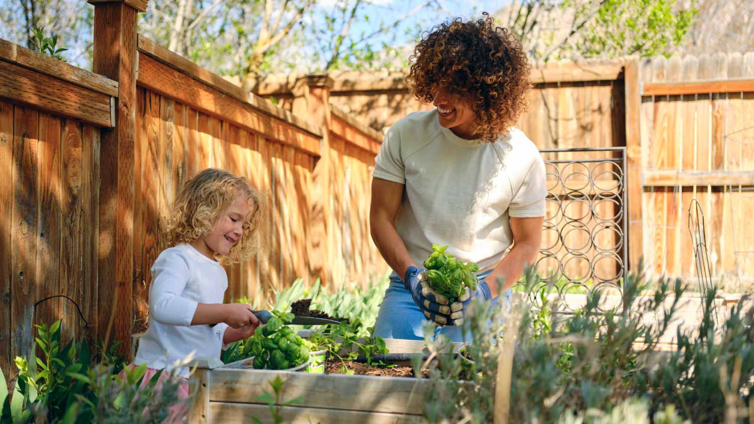 Mom and daughter planting herb plants in a backyard