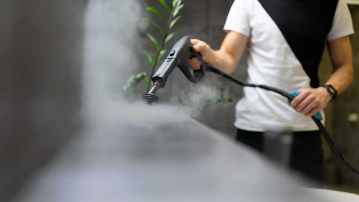 Worker cleaning the tiles in the bathroom with steam
