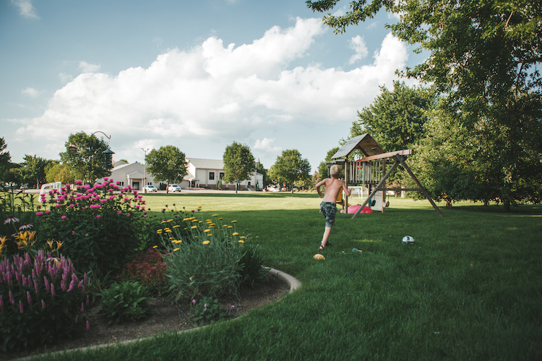 Young boy in grassy backyard with play set in background
