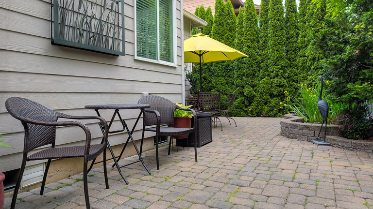 Backyard patio with chairs and table on brick pavers