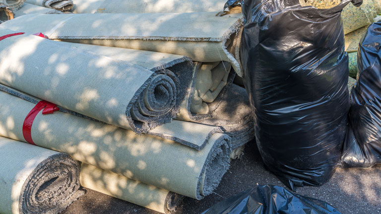 carpet thrown out by trash on driveway 