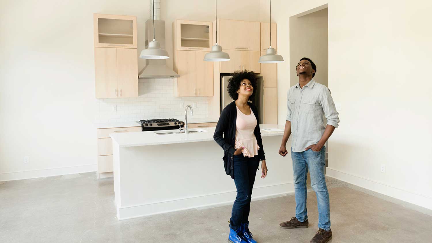 Couple standing in the kitchen of a new condo inspecting the ceiling