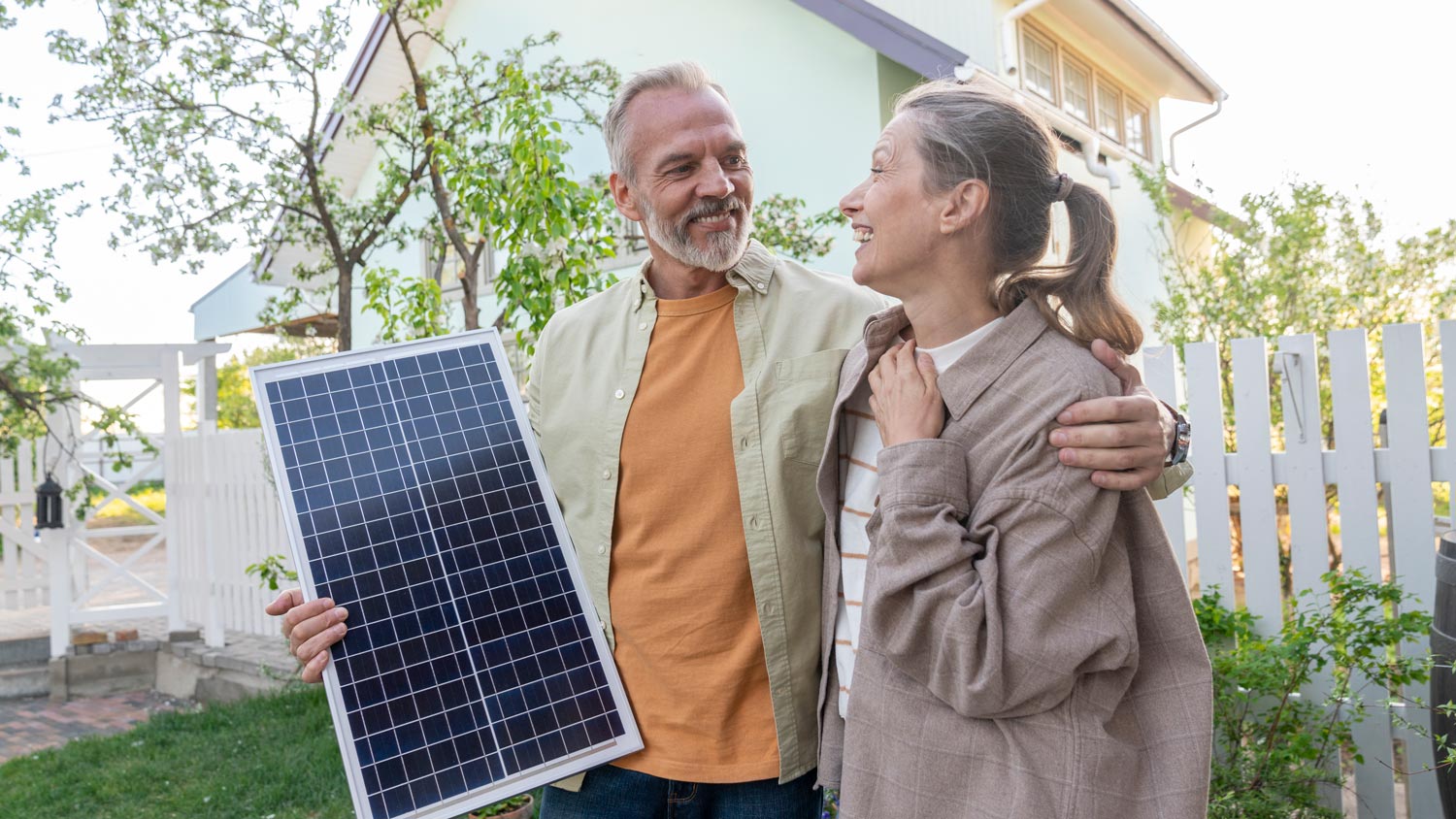Happy couple with solar panel in front of house