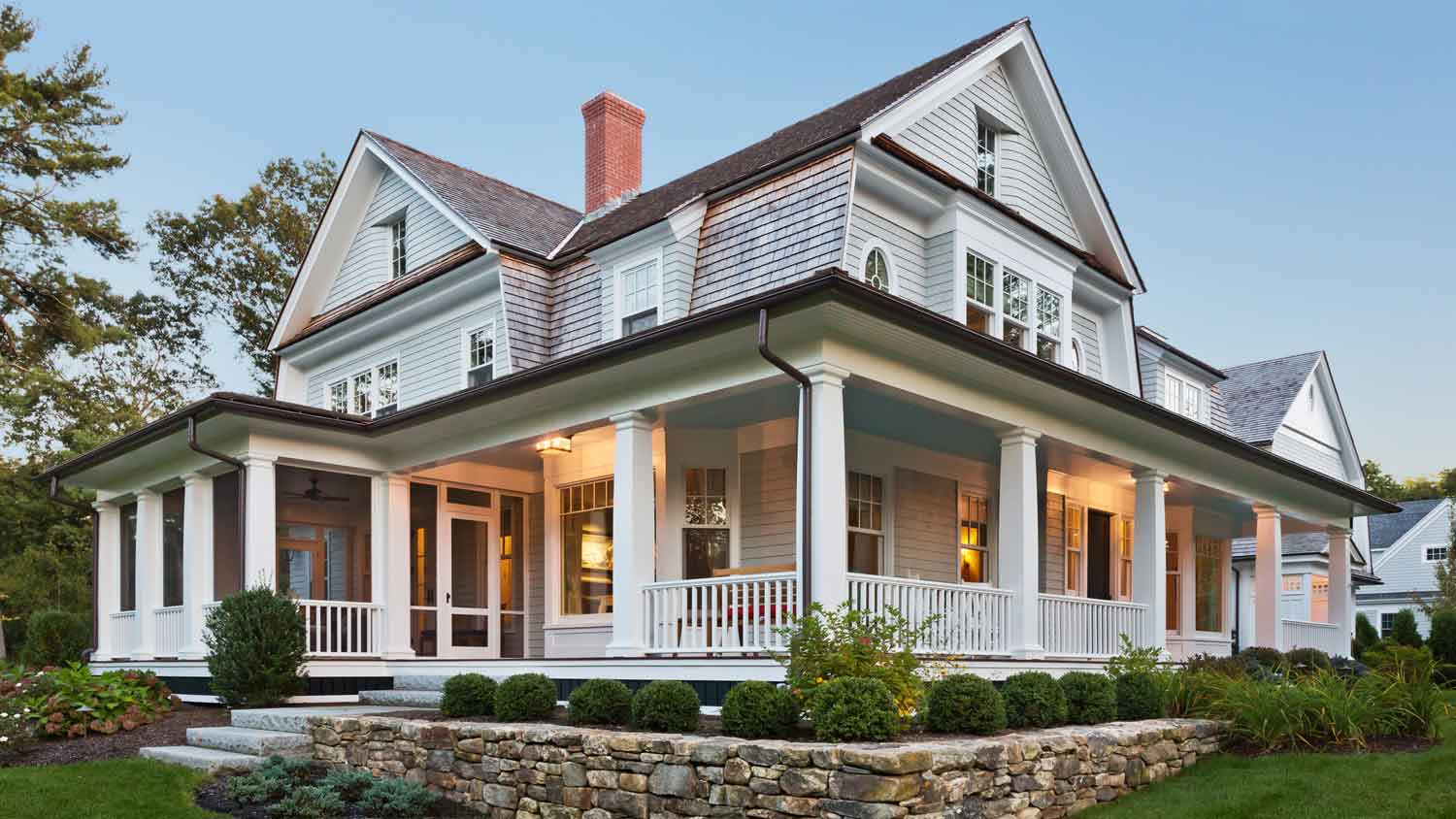 The exterior of a house with outdoor lighting and a lanscaped garden