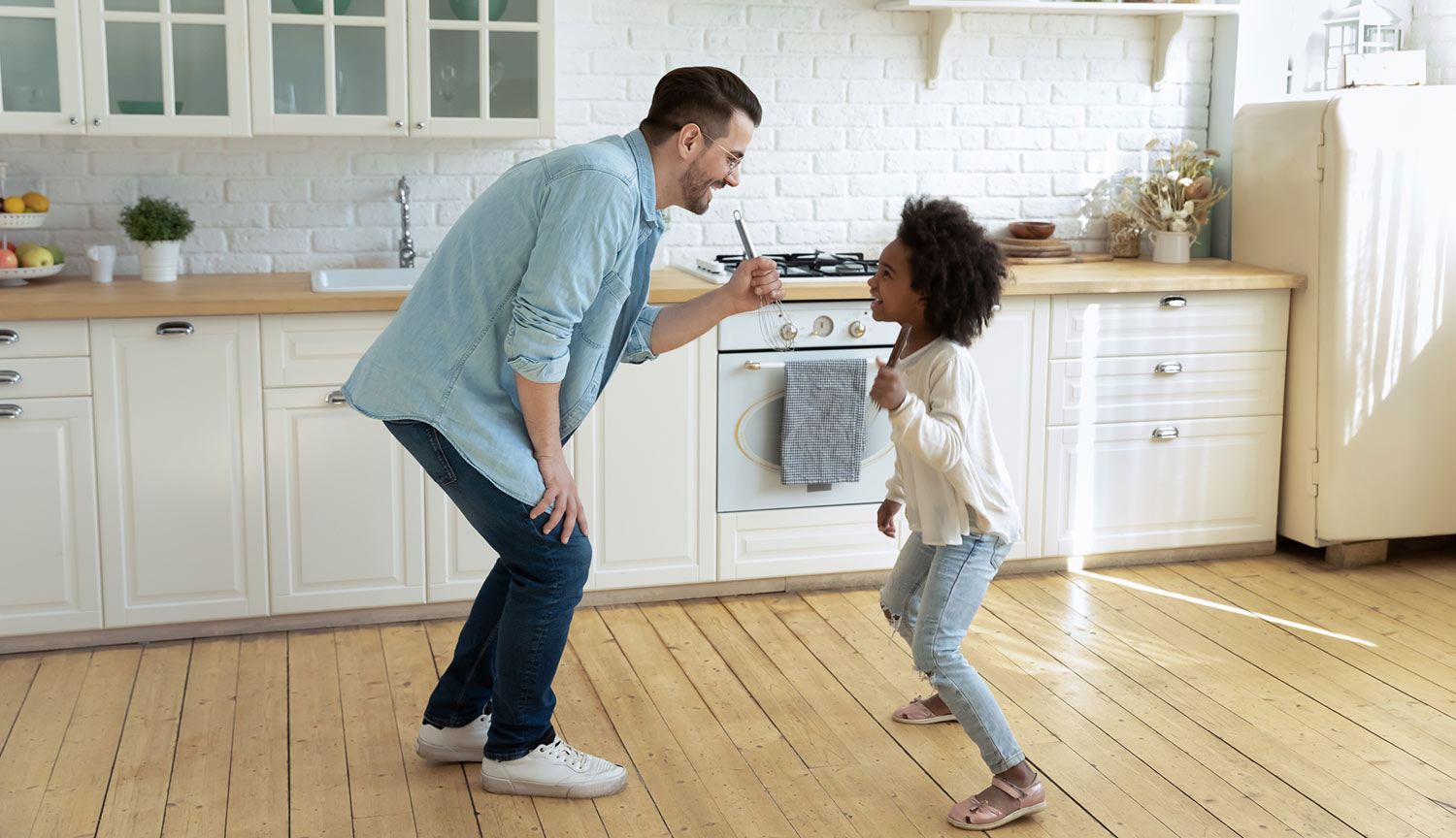 Father and daughter have a dance party on kitchen floors