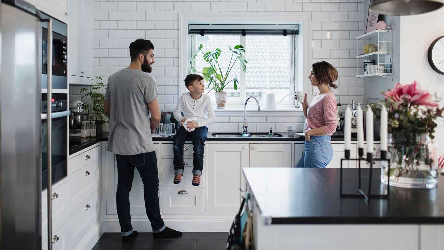 Family hangs out in kitchen with black granite