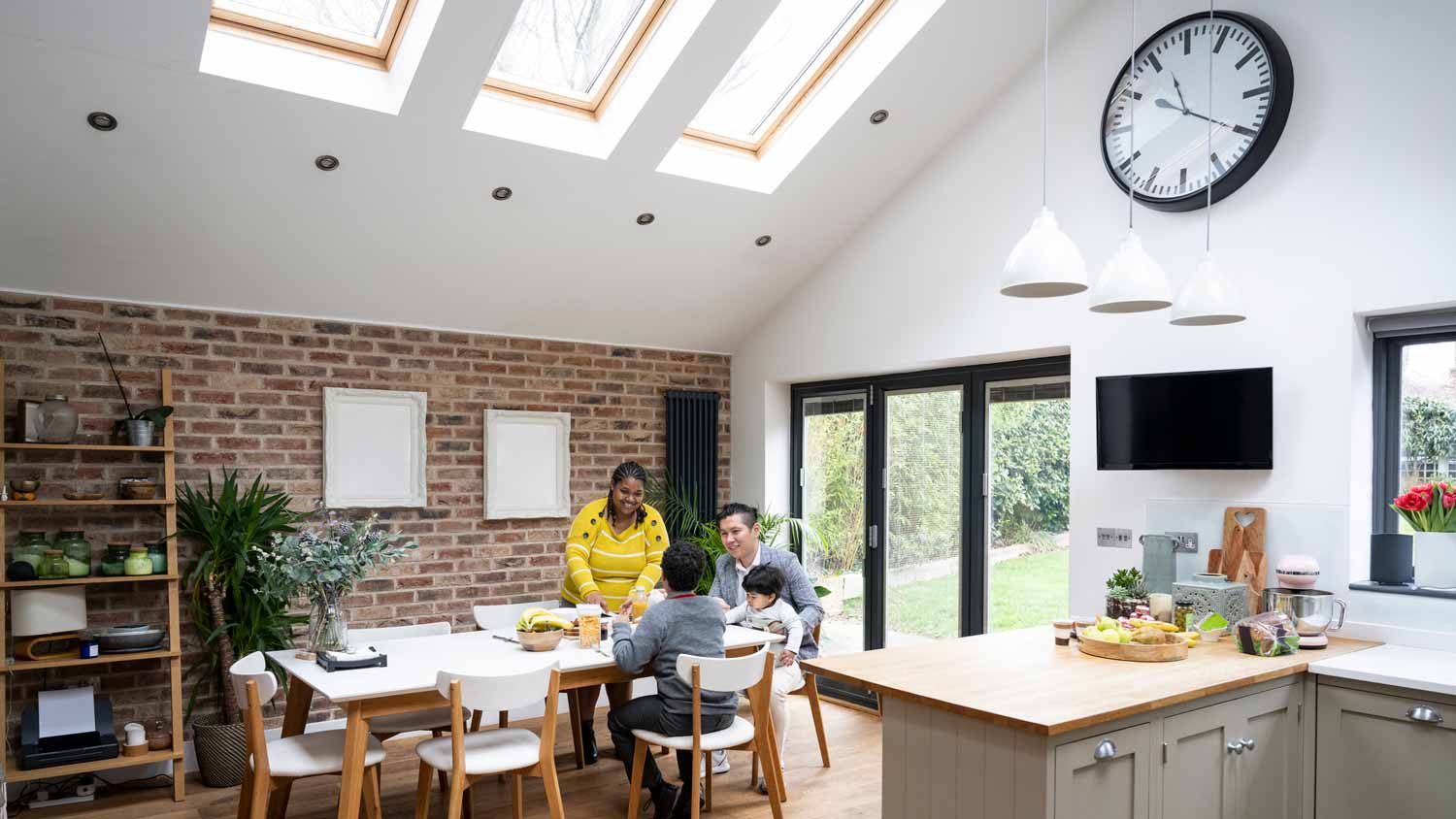 A family having breakfast in the kitchen below a skylight