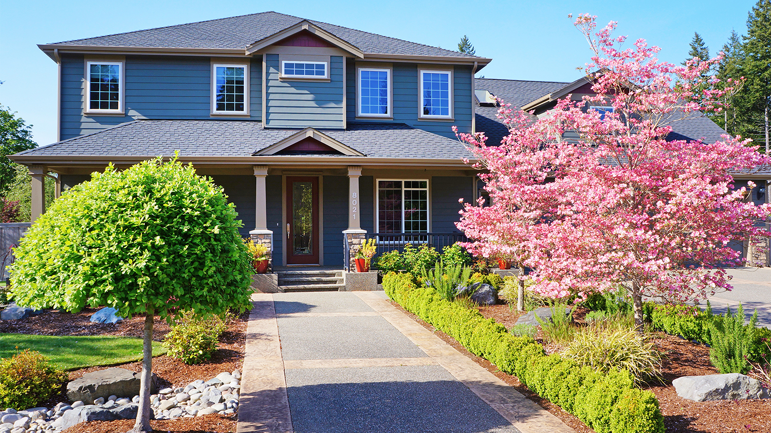 grey large house with beautiful landscaping  