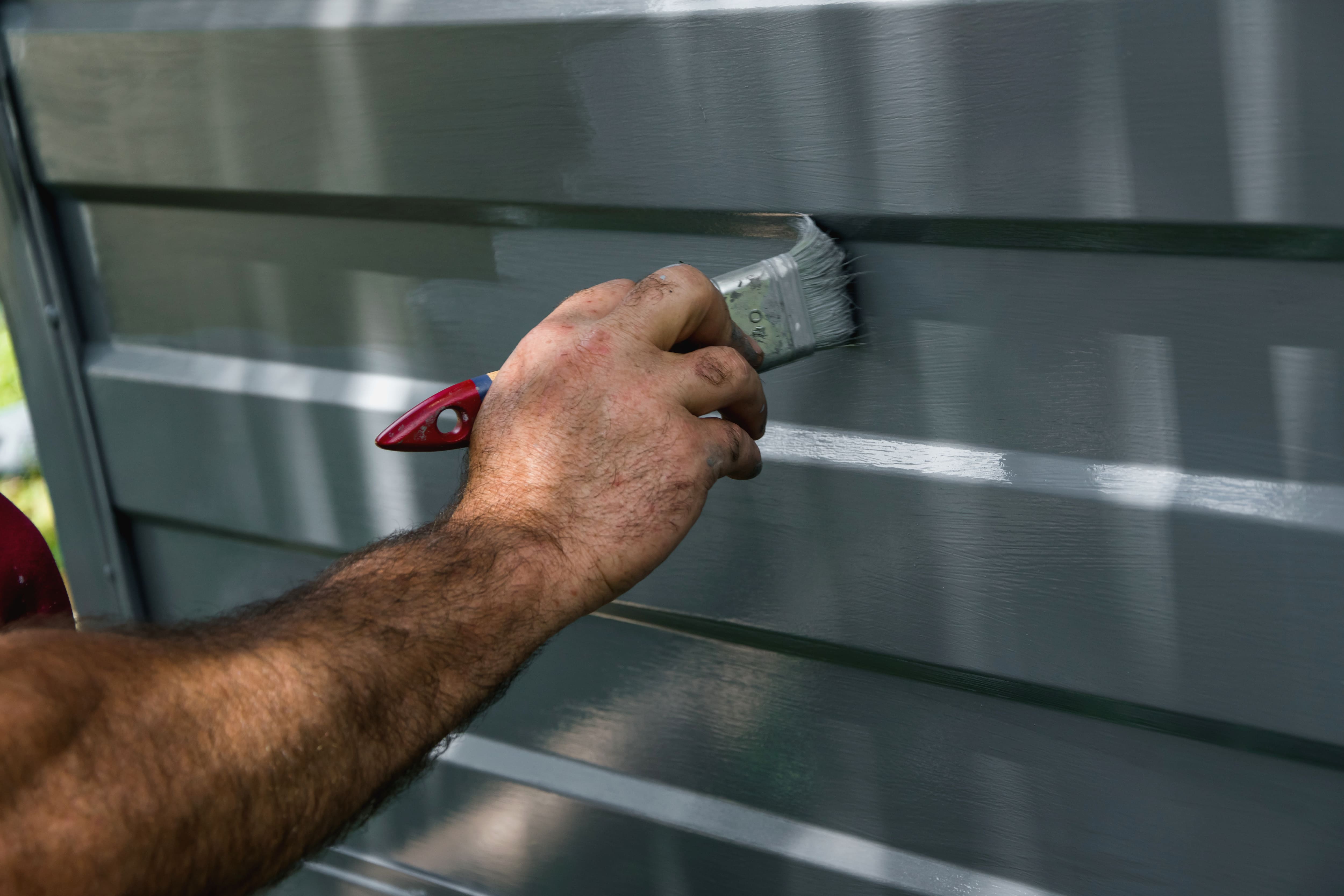 Painter painting a garage door with a brush