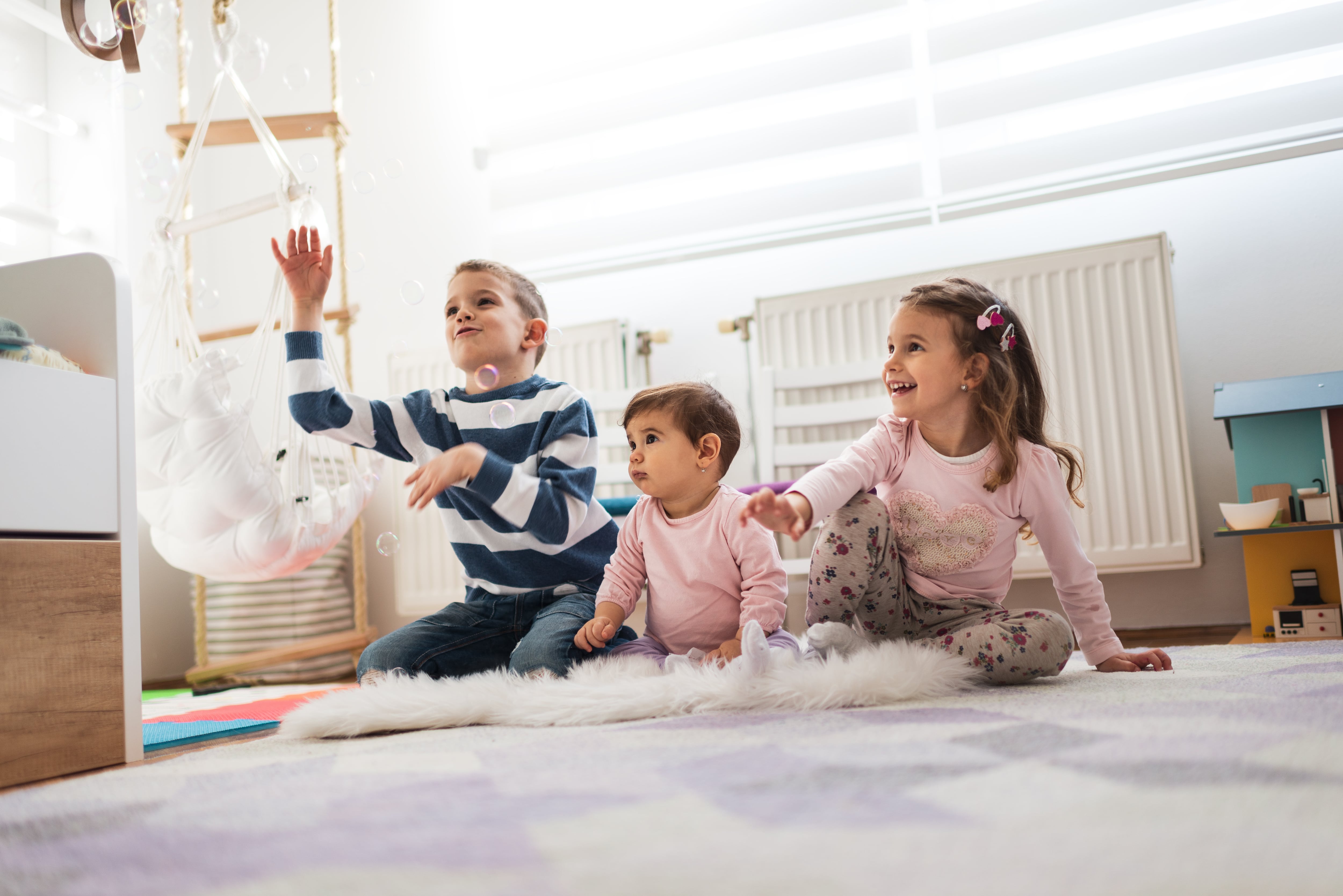 Brother and sisters playing with bubbles in room