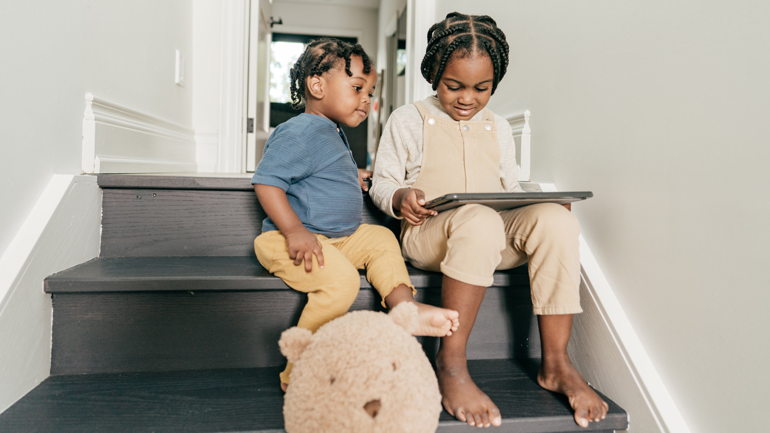 Siblings sitting on staircase with tablet
