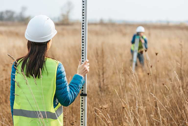 surveyors with survey ruler and digital level in field