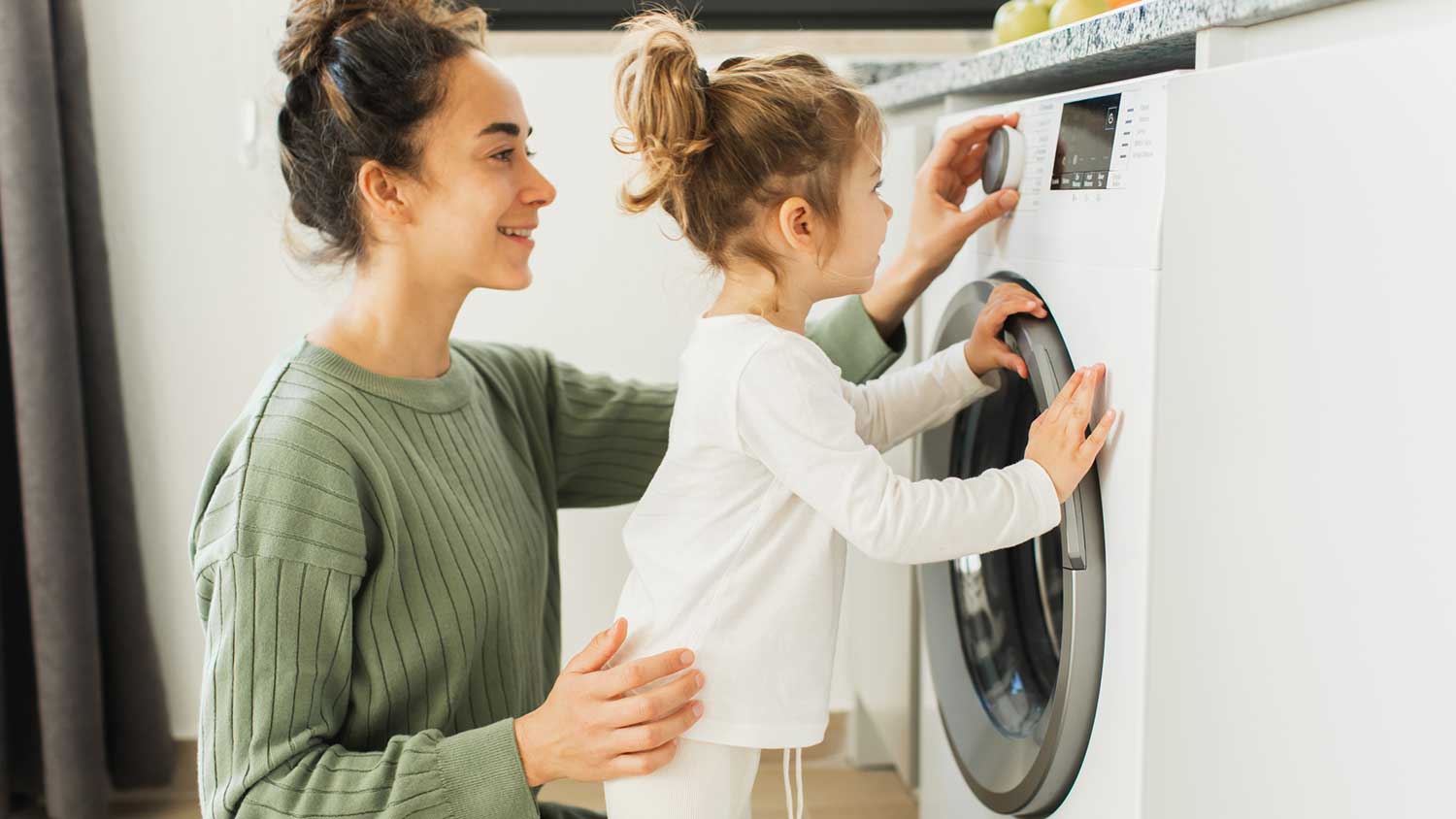  Daughter helping mom loading the dryer