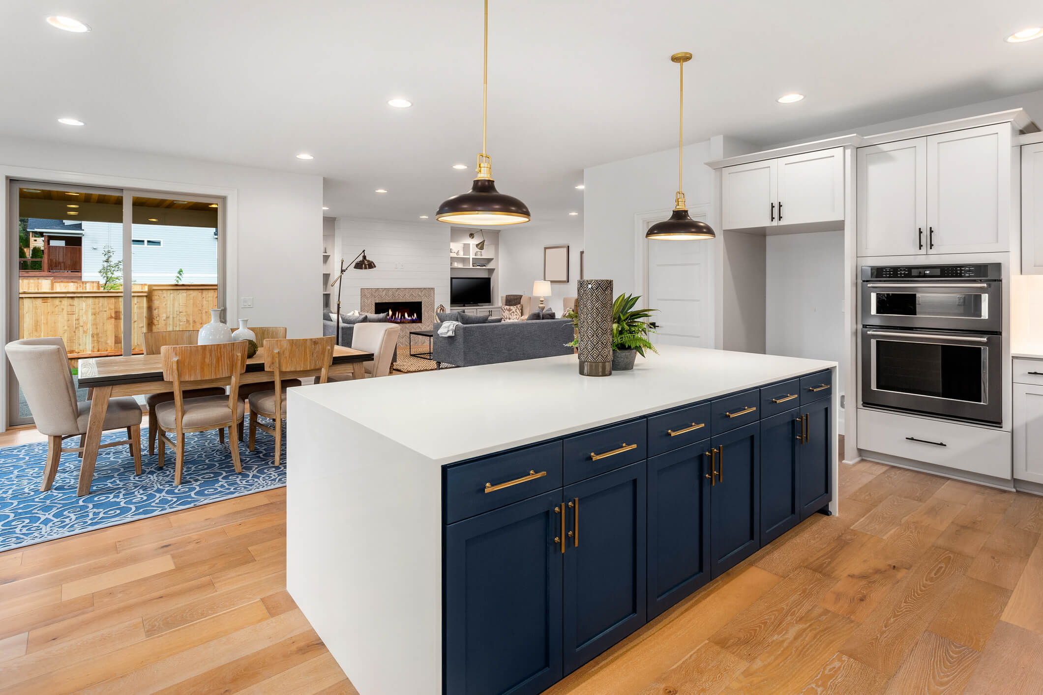 beautiful kitchen in new luxury home with large island, pendant lights, and hardwood floors. Shows dining area and living room