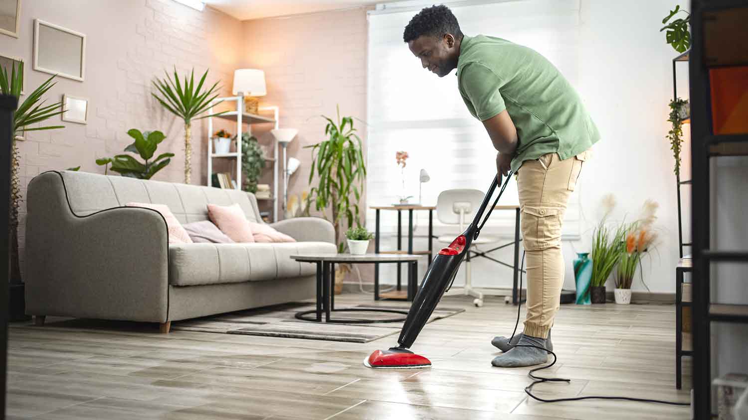 Man using steam mop to clean the floor in the living room