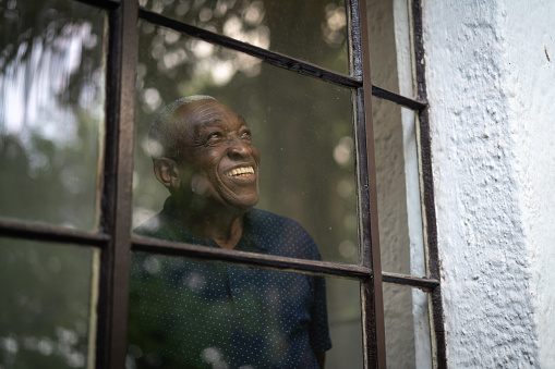 A smiling man is looking out a large window