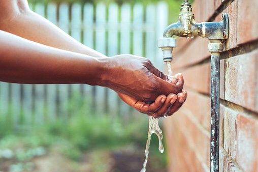 Man uses outdoor faucet to rinse hands