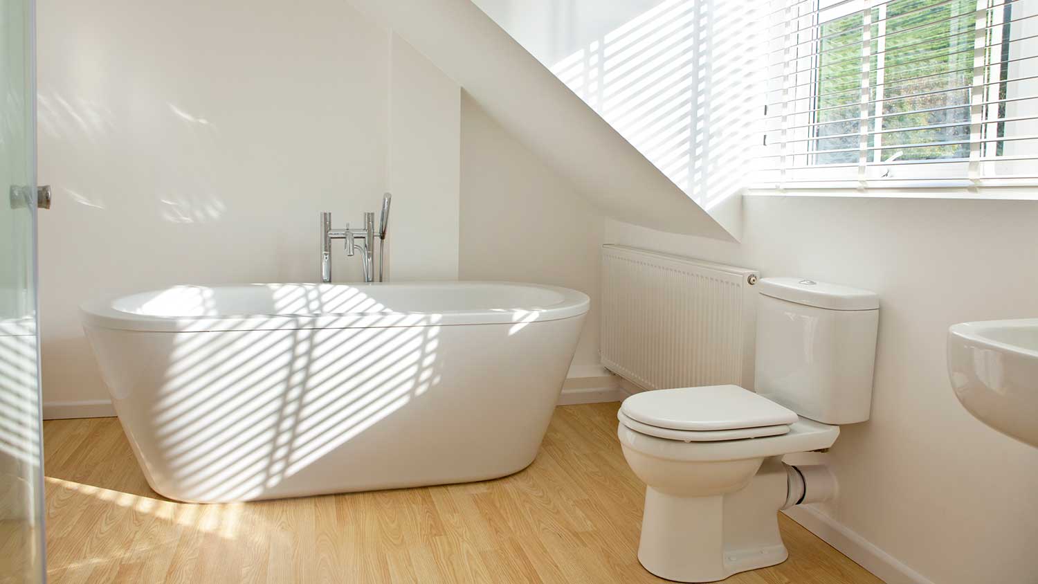 Modern white bathroom with bathtub and wooden floor