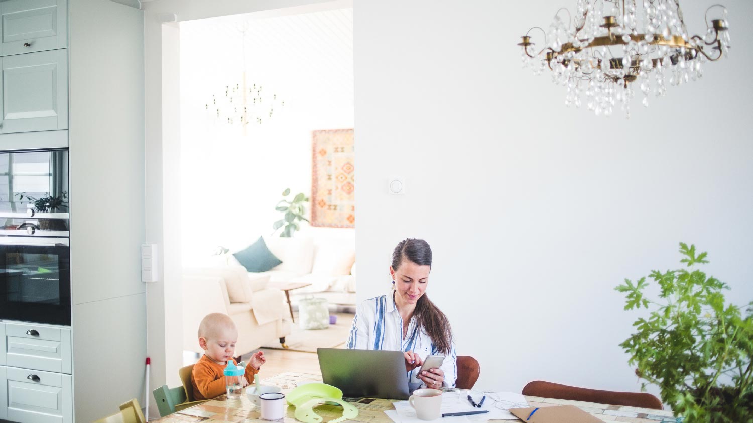 A mother working from home in a kitchen with a chandelier