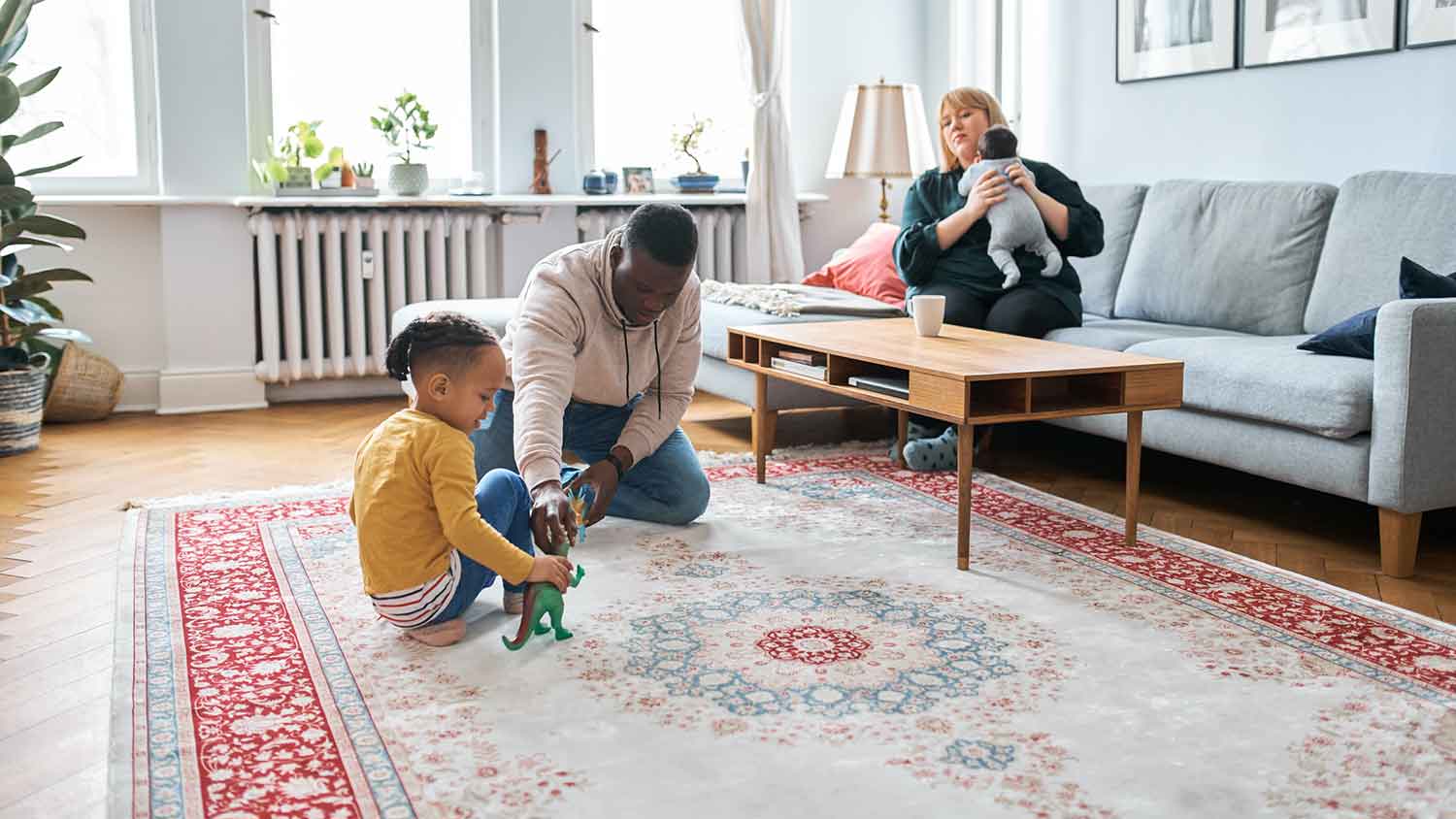 Father and son sitting on a rug playing with toys