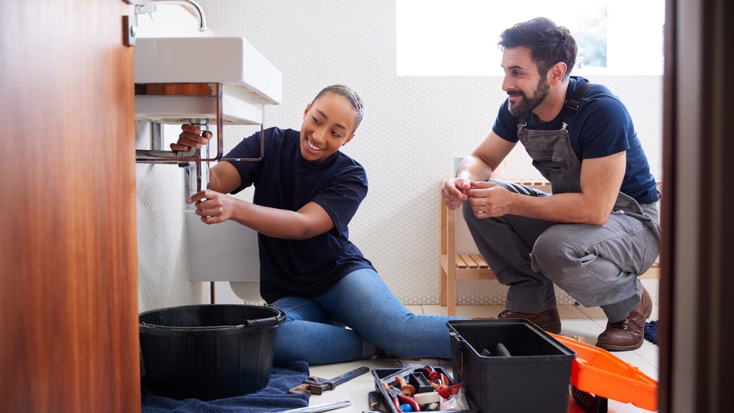 Plumbers fixing water pipes in a bathroom sink