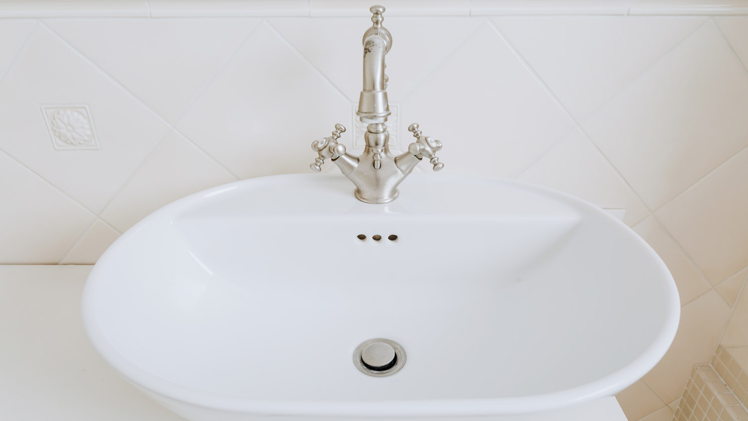A porcelain bathroom sink with an old style tap