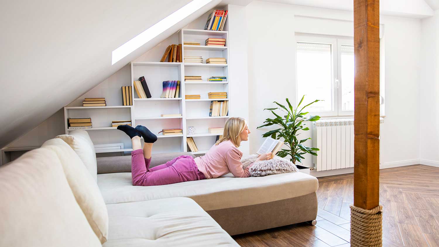 Woman lying on the couch is reading a book