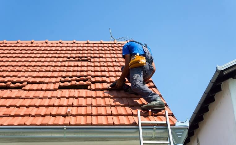 Roof repairman fixing a tile roof