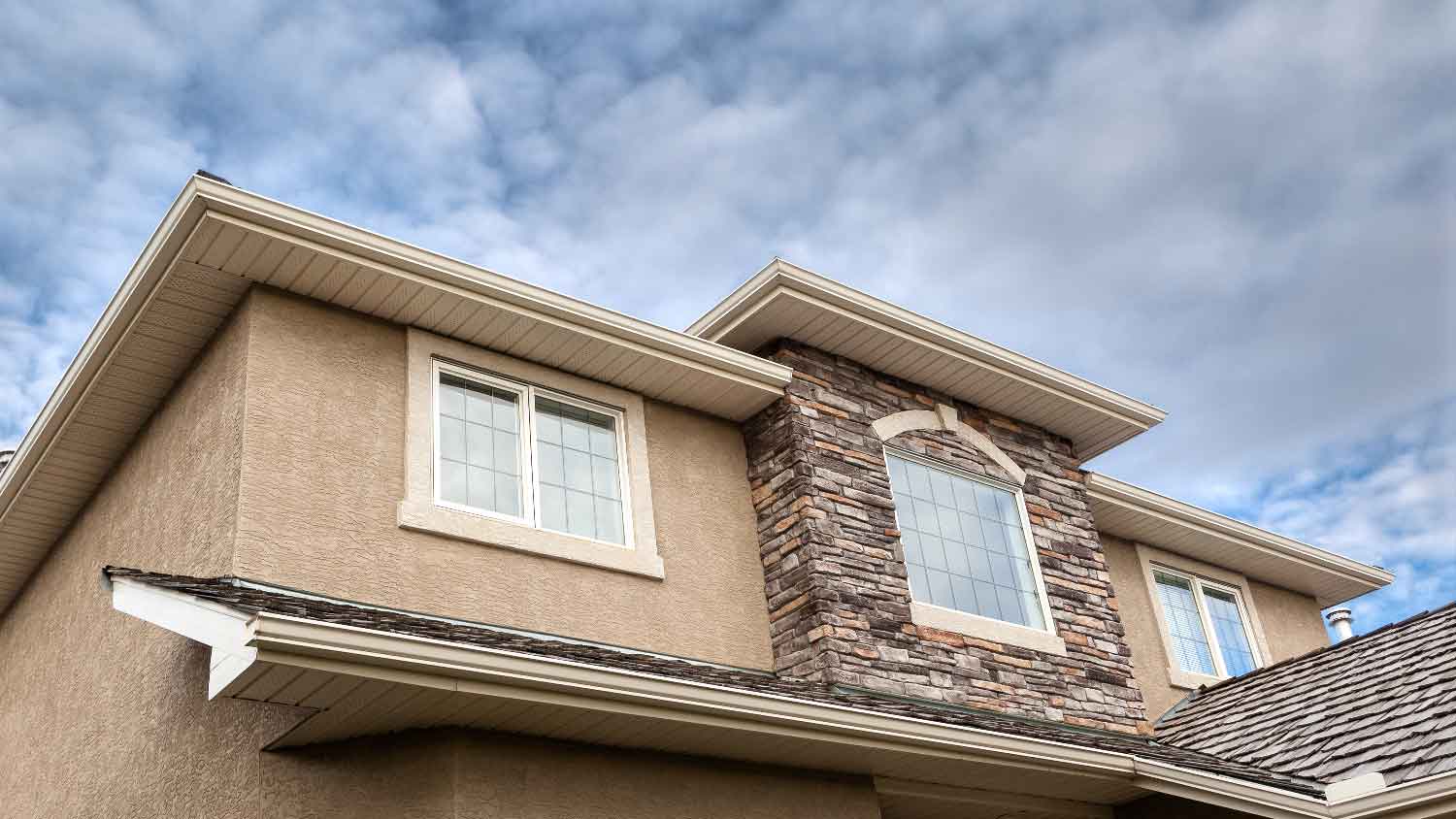 A stucco house with its roofline visible showing gutter and soffit