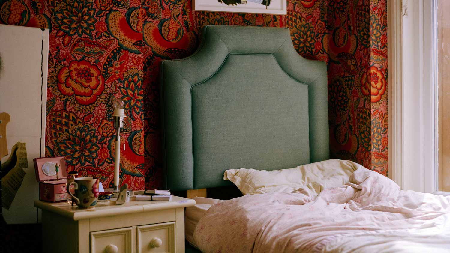 A teenage girl’s bedroom with wallpaper behind the bed 