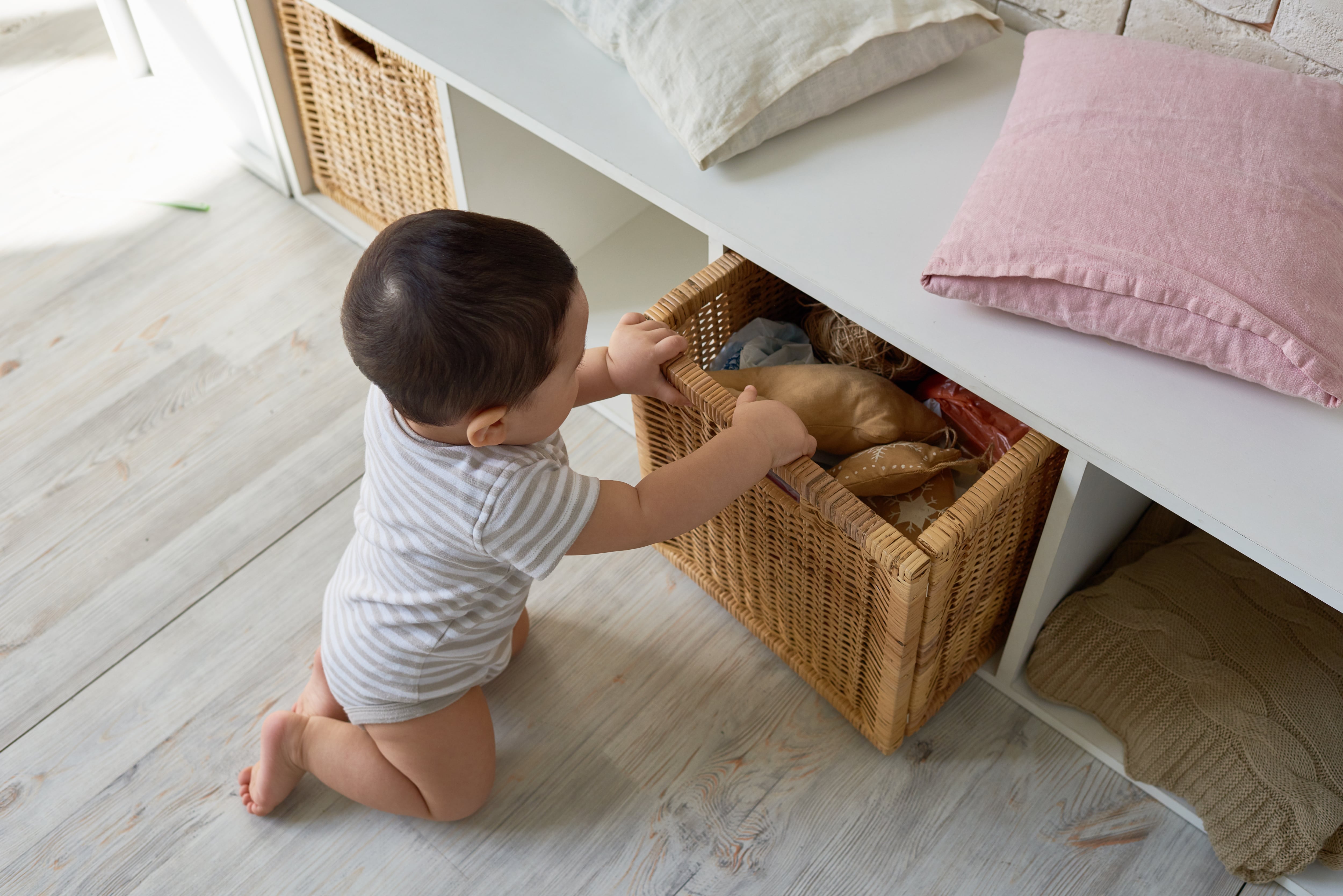 A young child going through a toy-filled basket underneath a white wood bench