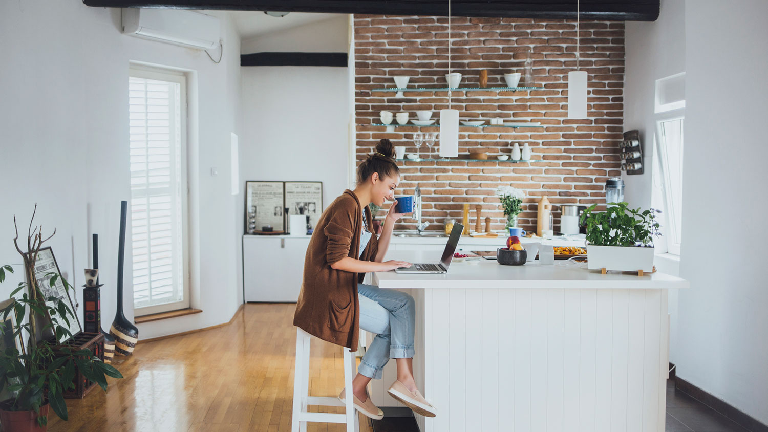 woman having coffee and using laptop in the kitchen