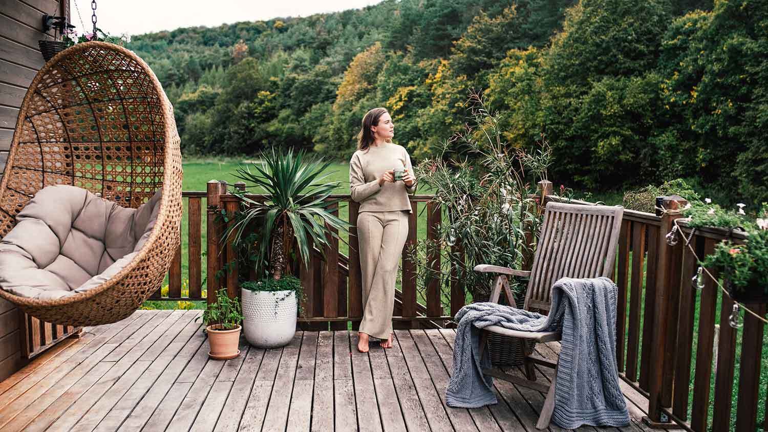Woman standing on a backyard deck enjoying coffee