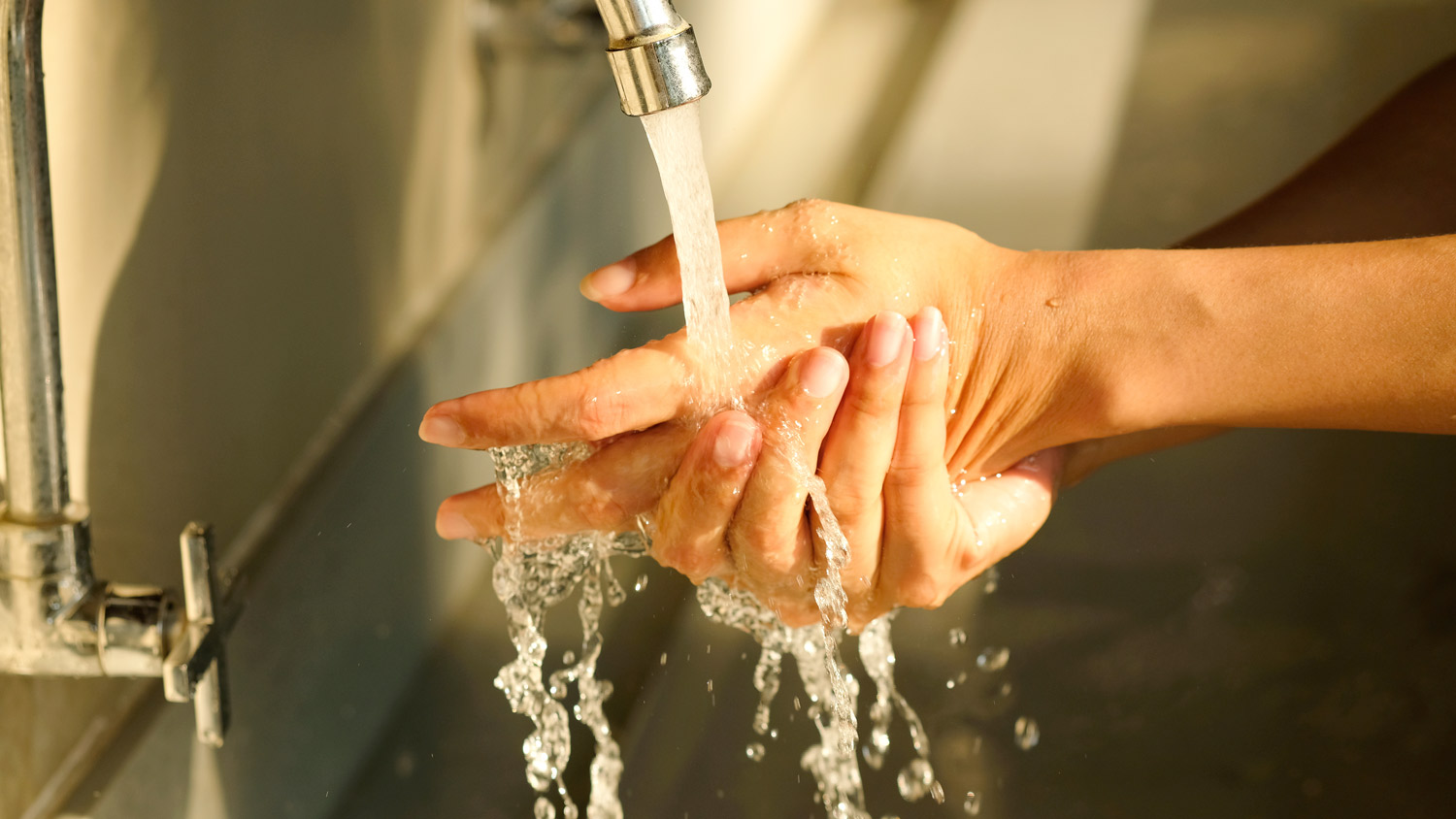 A woman washing her hand in a faucet