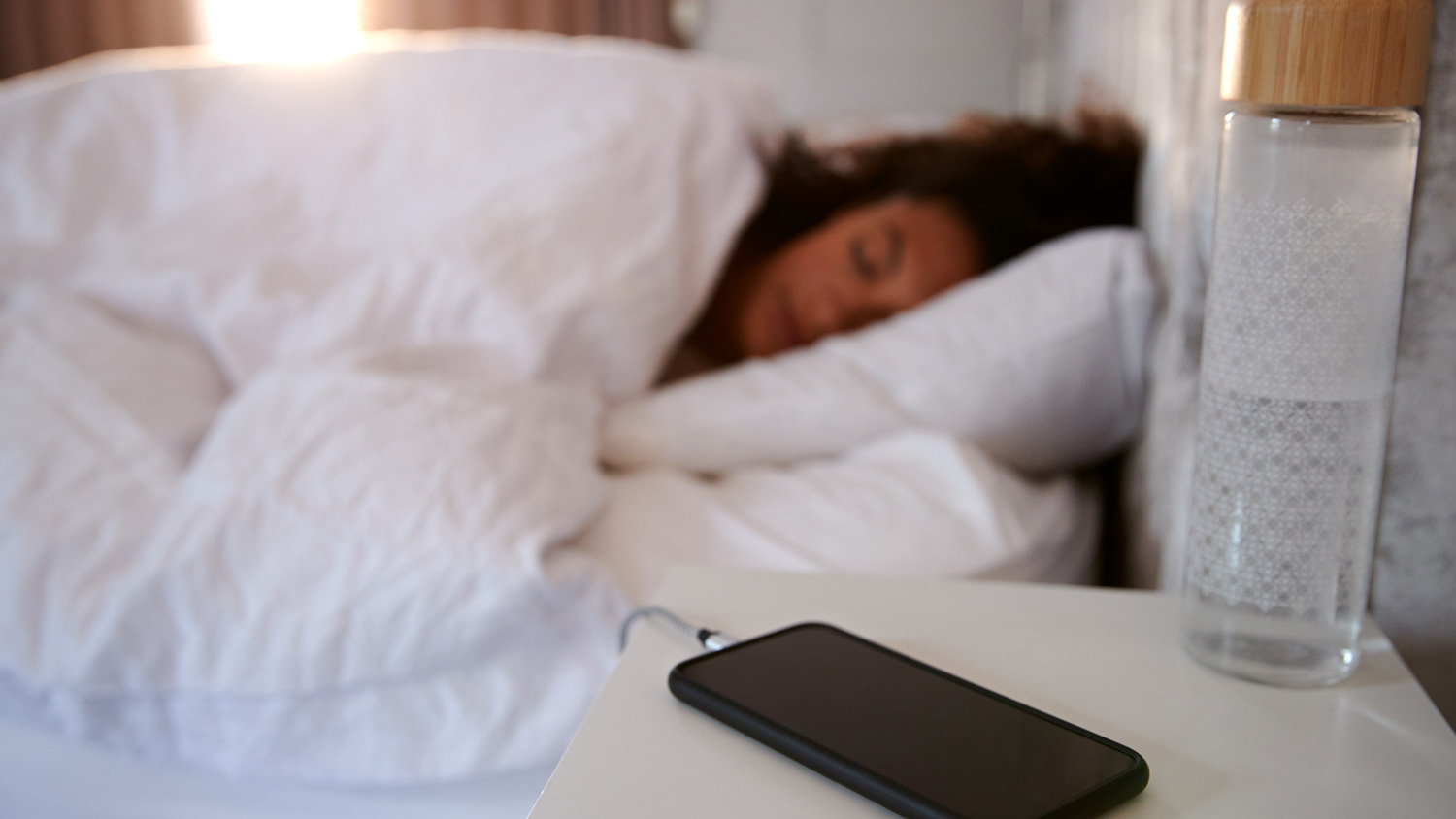 A woman sleeping while her phone is charging