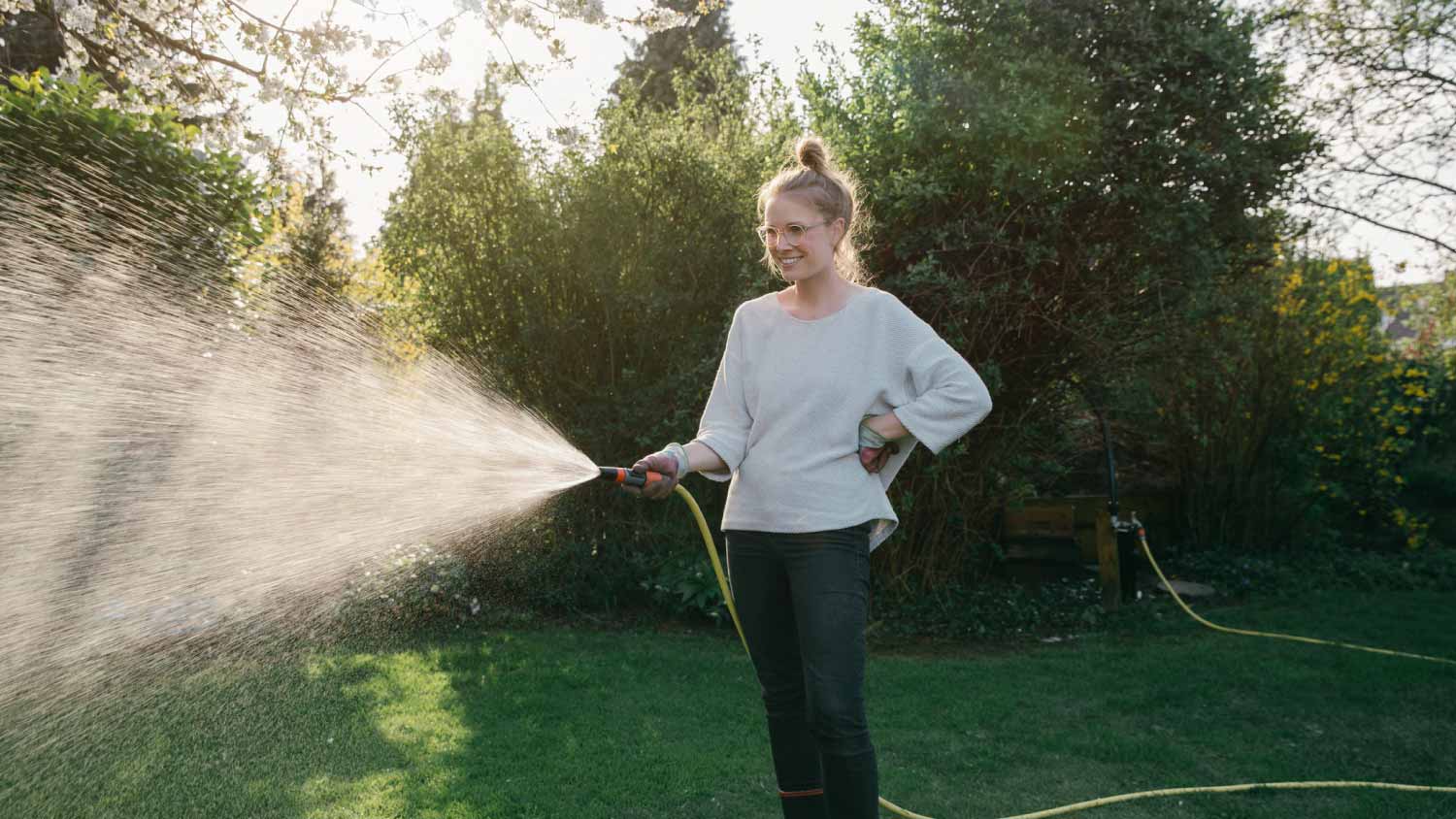 Woman sprinkling lawn in the garden
