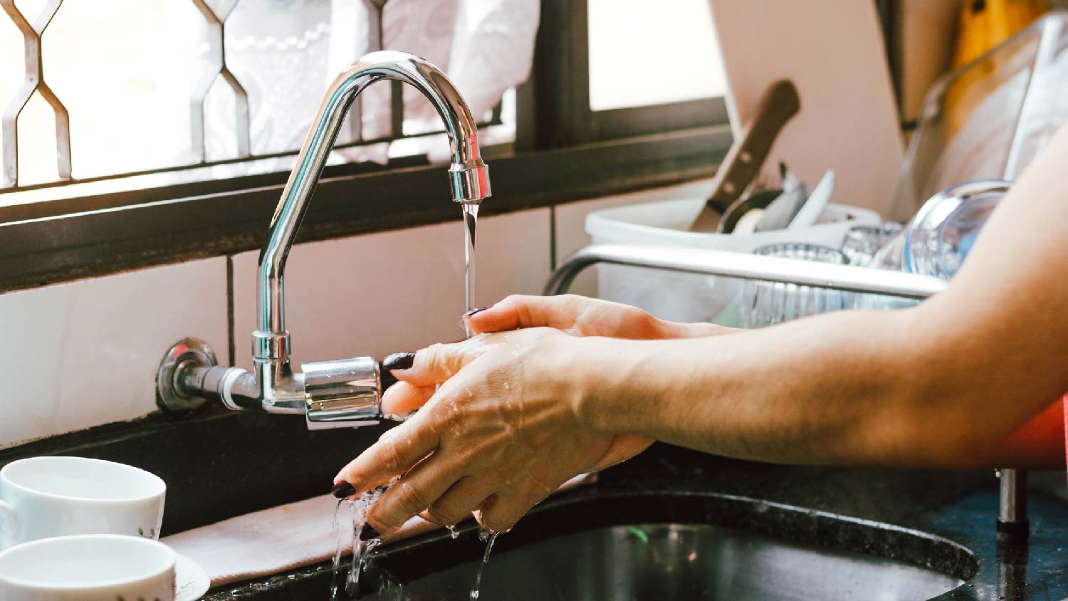 A woman washing her hands in the kitchen sink