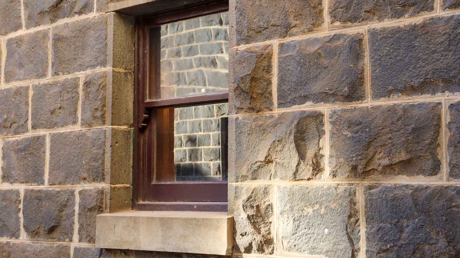 A wooden window on a bluestone wall