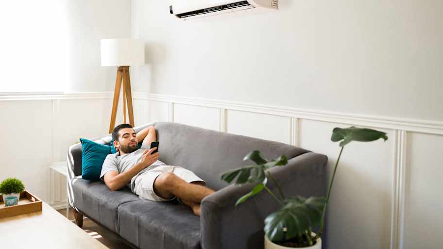 A young man relaxing on his sofa with the AC on